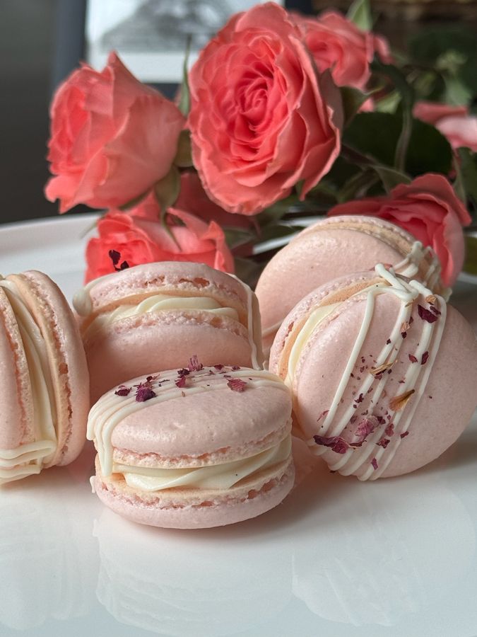 Pink salted honey rose macarons beside fresh roses