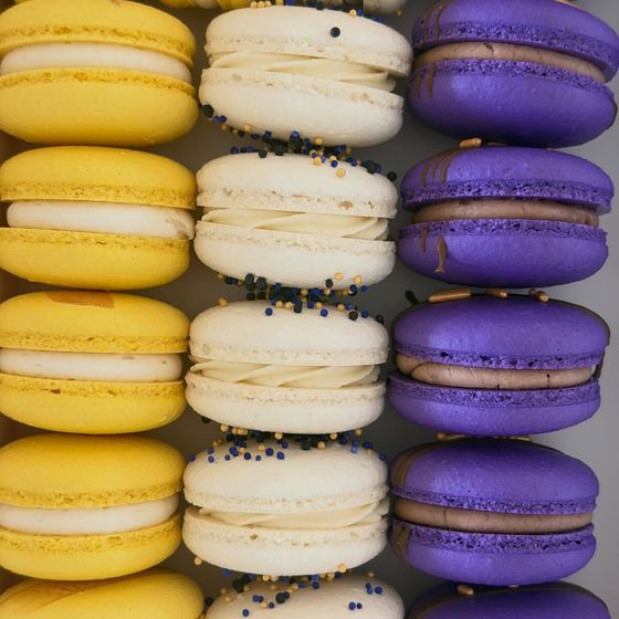 Rows of yellow, white, and purple macarons in school colors