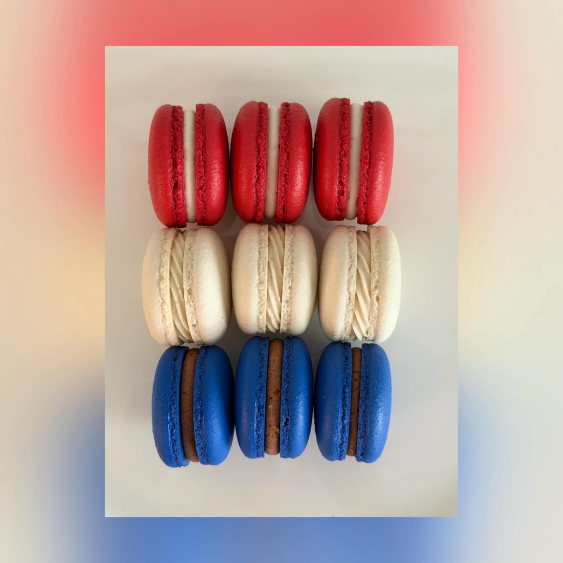 Three rows of red, white, and blue macarons on a soft gradient background
